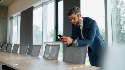 Homme dans une salle de réunion, en train de regarder son téléphone